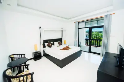 a bedroom with a bed and a large window at Phuket Monaburi Boutique Hotel in Rawai Beach