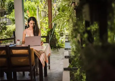 a woman sitting at a table using a laptop at Phuket Monaburi Boutique Hotel in Rawai Beach