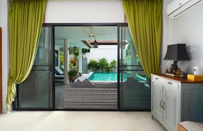 a living room with a swimming pool and green curtains at Nenuphar Villa by G Estate in Rawai Beach