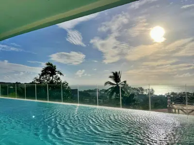 a swimming pool with a view of the ocean at Sunset Plaza by RESAVA in Karon Beach