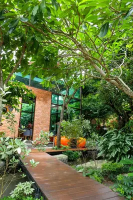 a garden with a wooden walkway and trees at Flora Ville-SHA PLUS in Chalong
