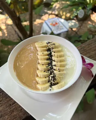 a white plate with a bowl of bananas on a table at Flora Ville-SHA PLUS in Chalong