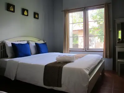 a bedroom with a large white bed with blue pillows at Flora Ville-SHA PLUS in Chalong