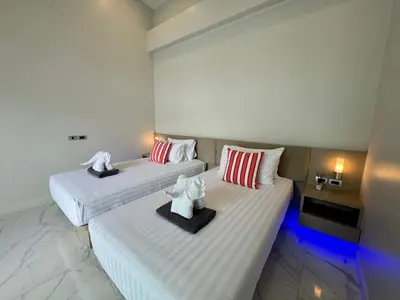 two beds in a hotel room with white sheets at Skypool Villa by G Estate Phuket in Nai Harn Beach