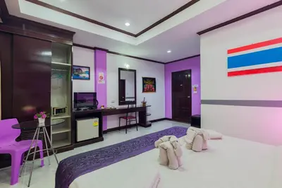 a bedroom with purple walls and a bed and a desk at Grand Orchid Inn Patong beach in Patong Beach