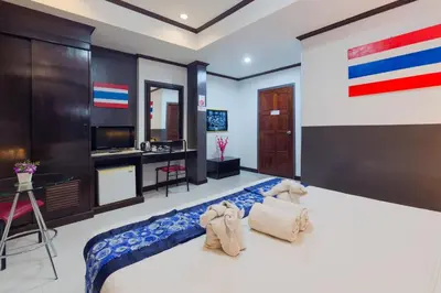 a bedroom with a large bed and a desk at Grand Orchid Inn Patong beach in Patong Beach