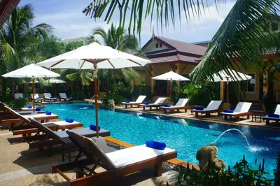 a swimming pool with lounge chairs and umbrellas at Le Piman Resort in Rawai Beach