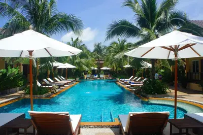 a swimming pool with lounge chairs and umbrellas at Le Piman Resort in Rawai Beach