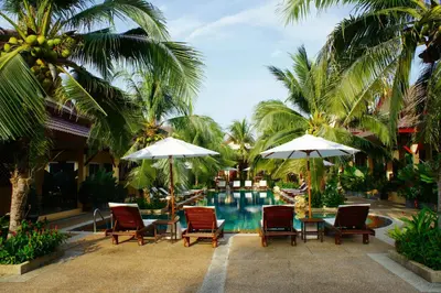 a pool at a resort with chairs and umbrellas at Le Piman Resort in Rawai Beach