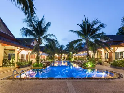 a resort pool with palm trees in the background at Le Piman Resort in Rawai Beach