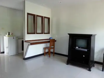 a living room with a tv and a table and a chair at C.A.P Mansion in Phuket Town