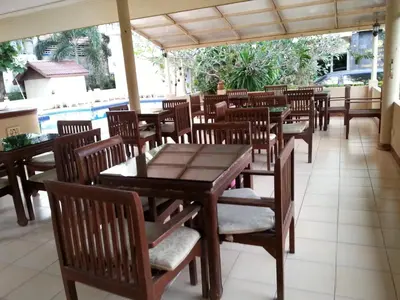 a restaurant with wooden tables and chairs and a pool at C.A.P Mansion in Phuket Town