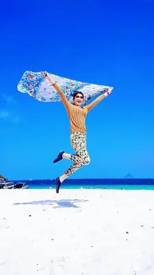 a man jumping in the air on a beach with a kite at Banhalawee in Ko Yao Yai