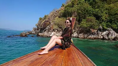 a woman sitting on the back of a boat in the water at Banhalawee in Ko Yao Yai