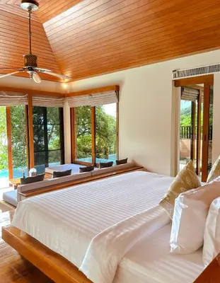 a bedroom with a large white bed with windows at Korsiri Pool Villas in Panwa Beach