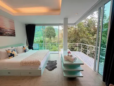 a bedroom with a bed and a balcony with windows at Peaceful Bliss in 81sqm Top Floor in Kamala in Kamala Beach