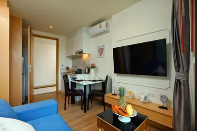 a living room with a blue couch and a tv at Cute Studio in Aristo Beach condo - 7 min walk to Surin Beach, construction view in Surin Beach
