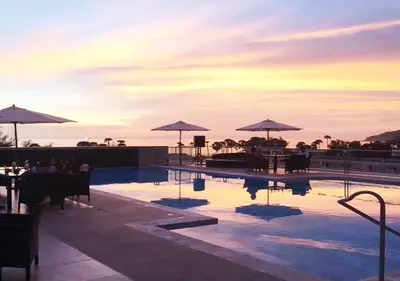 a pool with tables and umbrellas on top of a building at Grand Sunset Hotel Phuket in Karon Beach