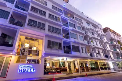 a large white building with a hotel sign on it at Grand Sunset Hotel Phuket in Karon Beach