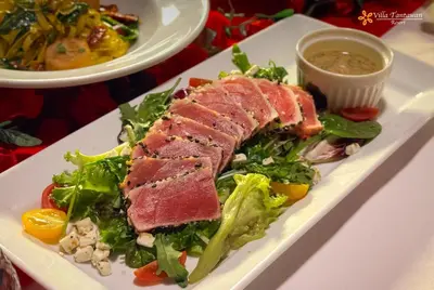 a plate of food with meat and salad on a table at Villa Tantawan Resort - Private Pool Villas in Kamala Beach