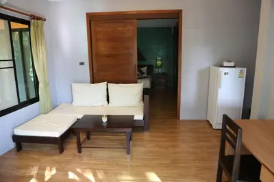 a living room with a couch and a table and a refrigerator at Cocoville Phuket - SHA Plus in Chalong