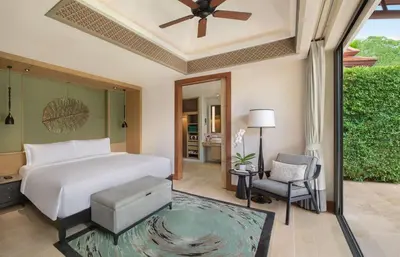 a bedroom with a white bed and a chair at Banyan Tree Phuket in Bang Tao Beach