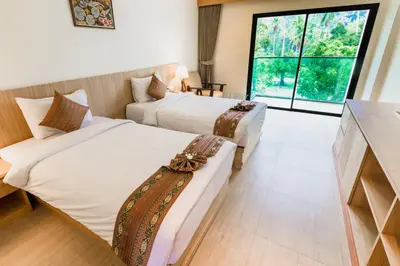 a hotel room with two beds and a large window at Airport Beach Hotel Phuket in Nai Yang Beach