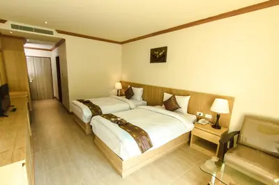 a hotel room with two beds and a television at Airport Beach Hotel Phuket in Nai Yang Beach