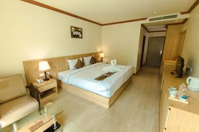 a bedroom with a bed and a chair in a room at Airport Beach Hotel Phuket in Nai Yang Beach