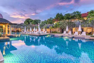 a pool at a resort with chairs and umbrellas at Phuket Kata Resotel in Kata Beach