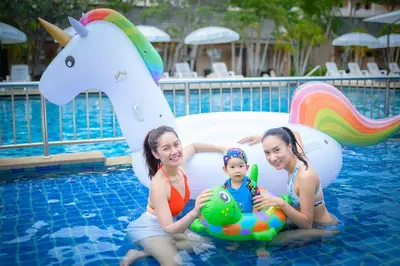 two women and a baby sitting in a swimming pool at Phuket Kata Resotel in Kata Beach