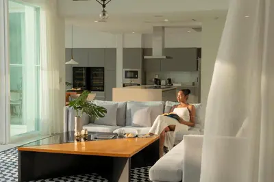 a woman sitting on a couch in a living room at Coastal Escape Natai Beach in Natai Beach