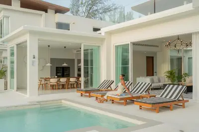 a woman sitting in chairs next to a swimming pool at Coastal Escape Natai Beach in Natai Beach
