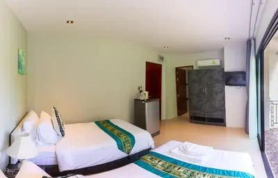a hotel room with two beds and a television at Rossarin Sea View Patong in Patong Beach