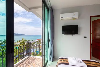 a bedroom with a balcony with a view of the ocean at Rossarin Sea View Patong in Patong Beach
