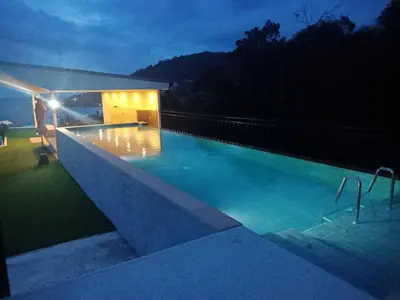 a swimming pool at night with the lights on at Rossarin Sea View Patong in Patong Beach
