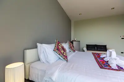 a bedroom with a bed with white sheets and pillows at Rossarin Sea View Patong in Patong Beach