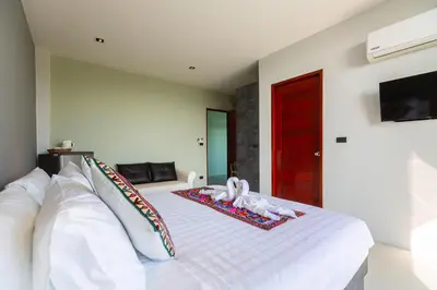 a bedroom with a white bed with a red door at Rossarin Sea View Patong in Patong Beach