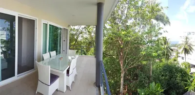 an open balcony with a glass table and chairs at Karon Beach Apartment Sea View in Karon Beach
