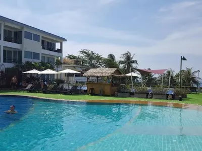 a person swimming in a large swimming pool next to a building at Karon Beach Apartment Sea View in Karon Beach