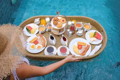 a tray of food on a table next to a pool at Metadee Concept Hotel in Kata Beach