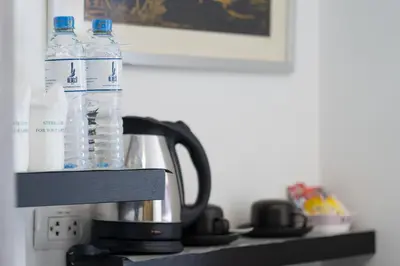a coffee maker with two bottles of water on a shelf at The BluEco Hotel SHA Plus in Kata Beach