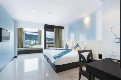 a bedroom with a bed and a table and a desk at The BluEco Hotel SHA Plus in Kata Beach