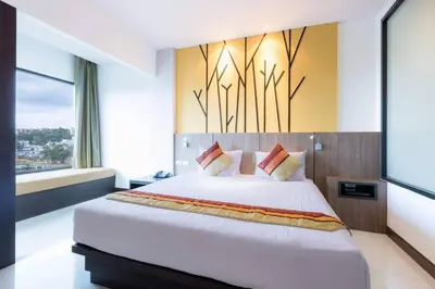 a bedroom with a large bed and a large window at The BluEco Hotel SHA Plus in Kata Beach