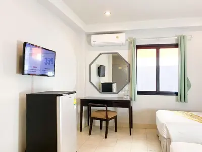 a room with a bed and a desk with a mirror at The Corner in Patong Beach