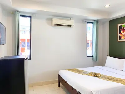 a bedroom with two beds and a window at The Corner in Patong Beach