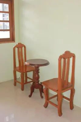 two wooden chairs and a table and a table and chairs at One One Hostel Patong in Patong Beach