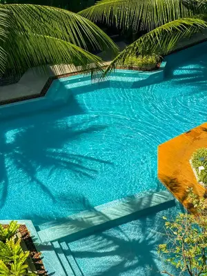 a swimming pool with blue water and palm trees at Diamond Resort Phuket Official Account in Bang Tao Beach