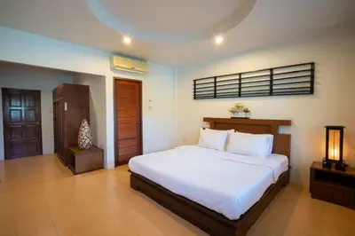 a bedroom with a large bed with white sheets at Surin House in Surin Beach