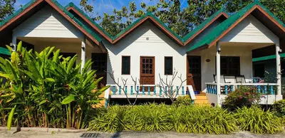 a small white house with a green roof at Surin House in Surin Beach